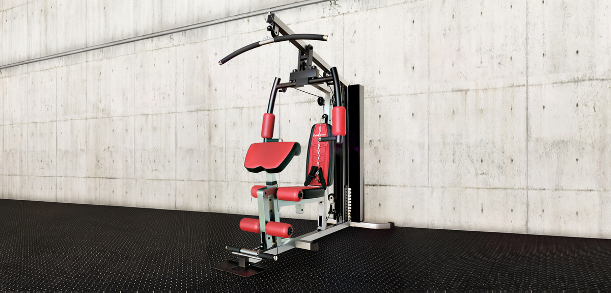 HGX100 Kraftstation mit Latzug, Butterfly und Beinstrecker vor einer Betonwand