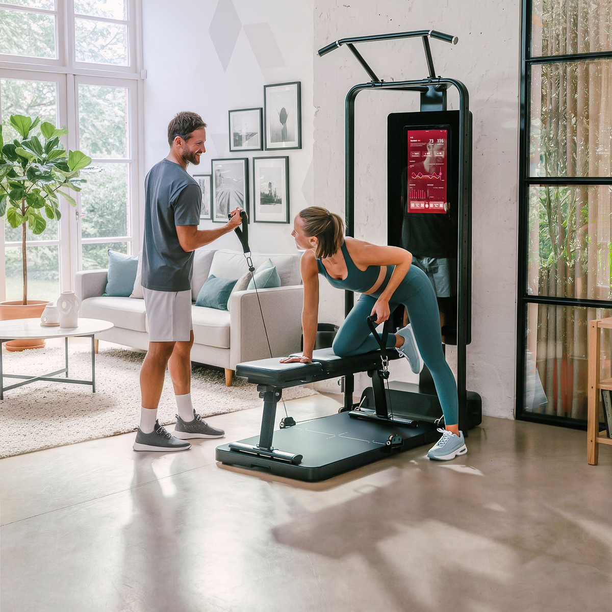 Paar an der sGym Pro, Frau rudert einarmig an der Bank