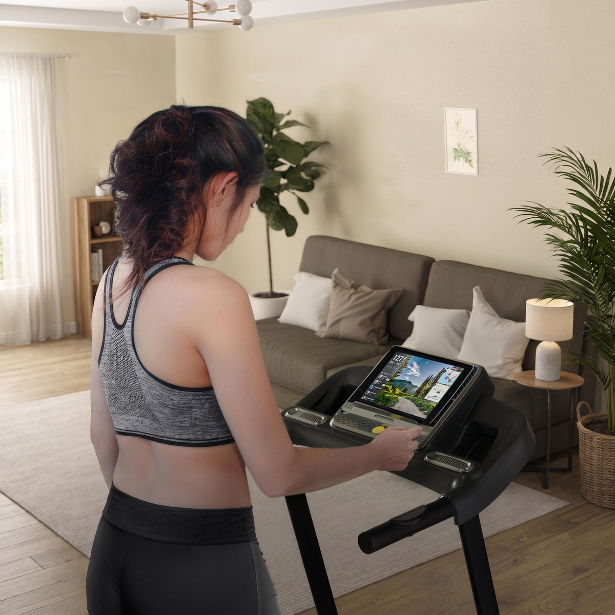 Frau startet ein Sportstech Live Workout am Tablet auf dem F10 Laufband