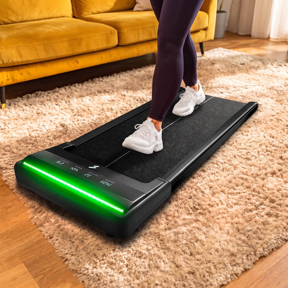 sWalk Lite Walking Pad im Wohnzimmer beim Gehen, grün leuchtende LED-Leiste und Display vorne