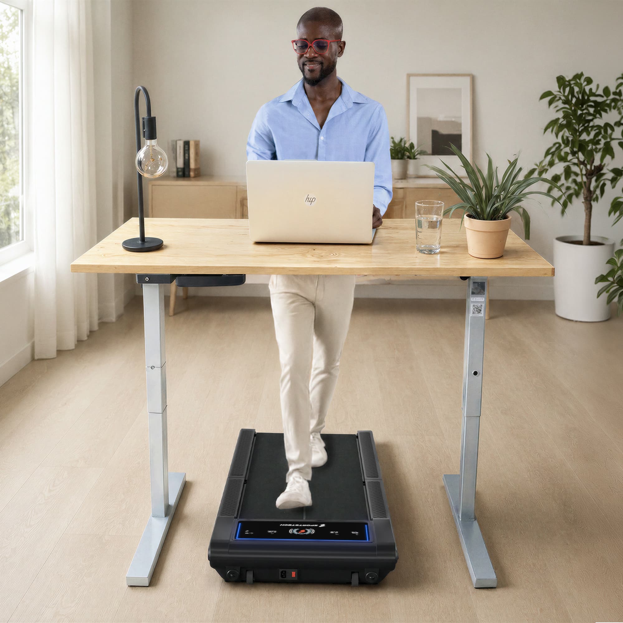 Mann am Laptop an Stehschreibtisch, gehend auf dem sWalk Fold Walking Pad im hellen Raum