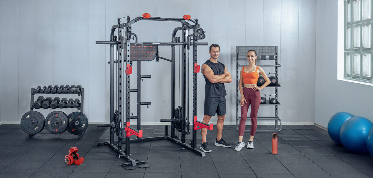 SXM150 Smith Machine im Home Gym, daneben ein Mann und eine Frau in Sportkleidung