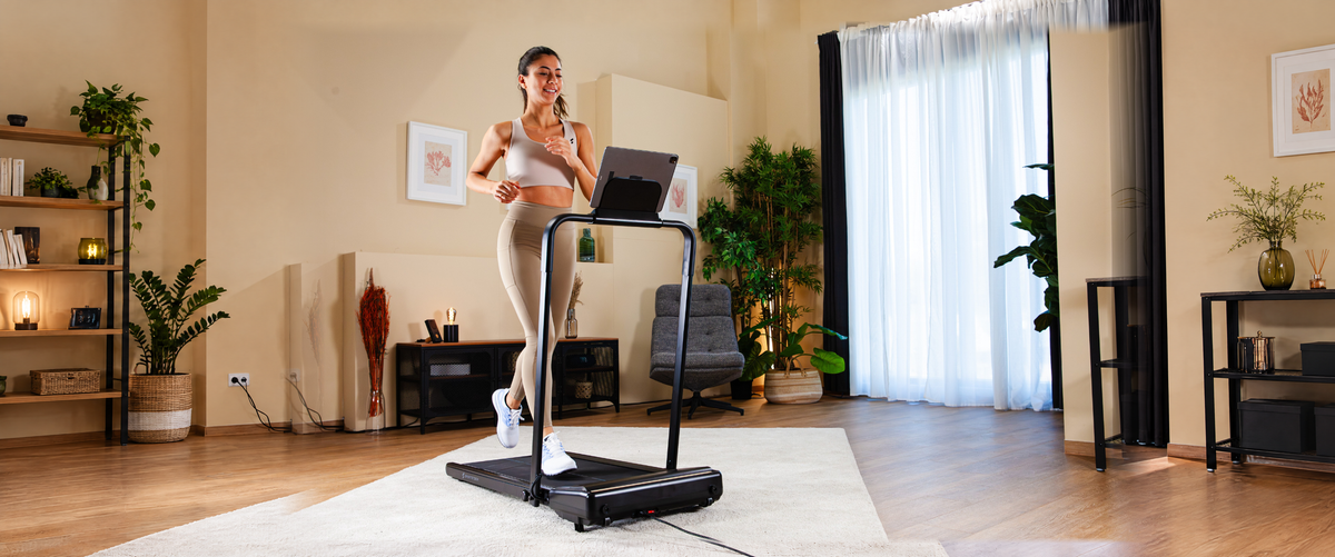 Frau trainiert auf einem Sportstech Laufband im Wohnzimmer