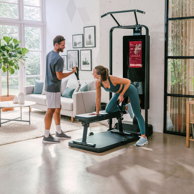 Paar an der sGym Pro, Frau rudert einarmig an der Bank