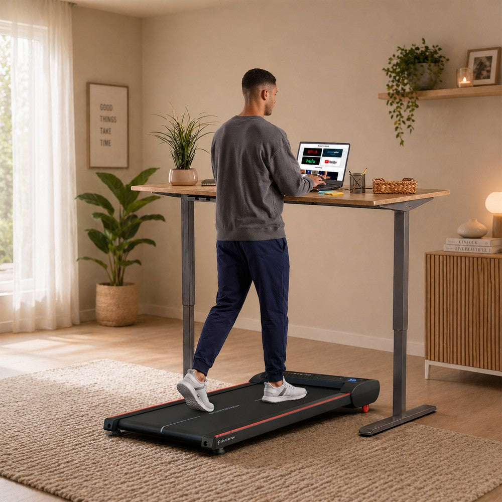Sportstech Walkmate Laufband unter einem Stehschreibtisch im Wohnraum, Mann beim Walking