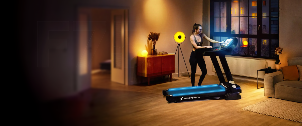 F37s Laufband mit blau beleuchteter Lauffläche, Frau bedient die Konsole im Wohnzimmer am Abend