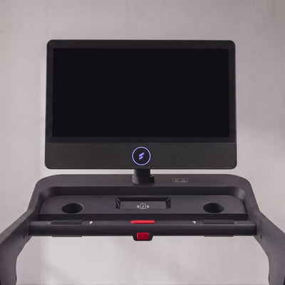 Frau trainiert im Ausfallschritt neben dem sTread Pro, auf dem Touchdisplay laeuft ein gefuehrtes Workout