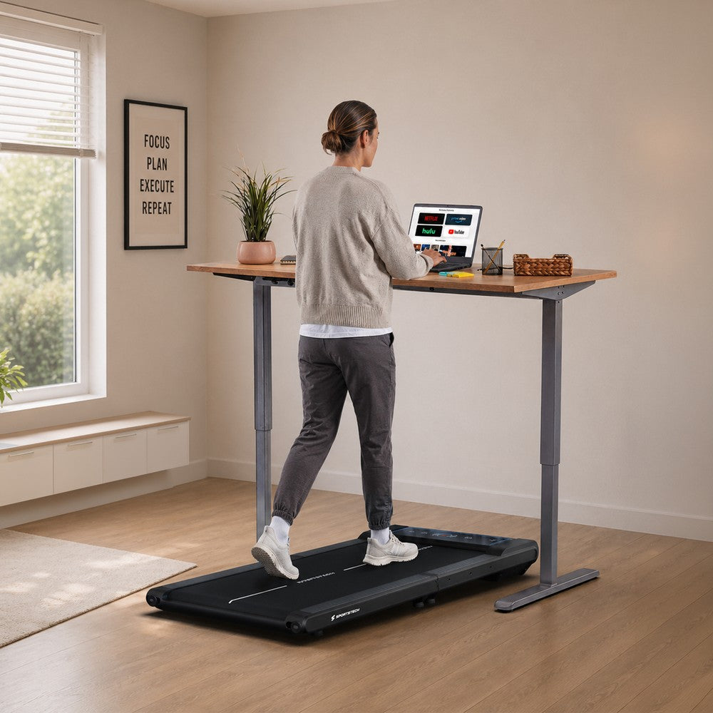 Sportstech sWalk Fold Laufband unter einem Stehschreibtisch im Wohnraum, Frau beim Walking