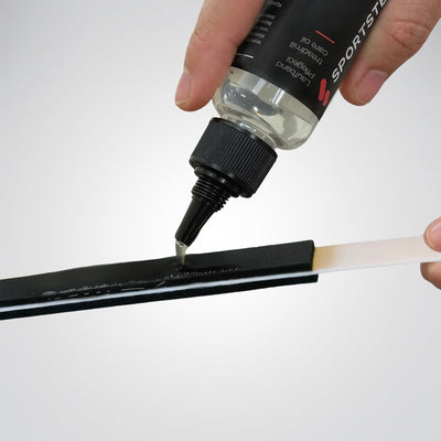 Silikonöl wird aus der Spitztülle auf den schwarzen Filzbelag des weißen Applikatorstabs aufgetragen