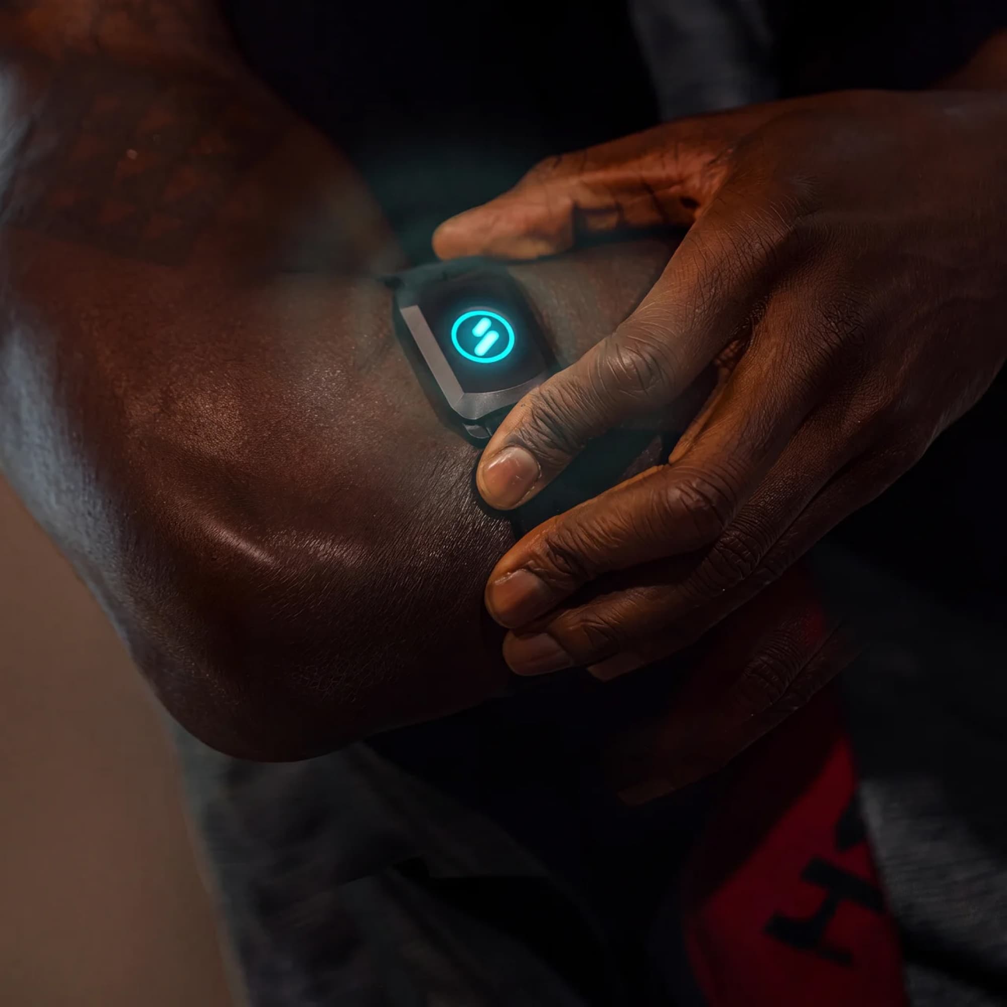 sPulse Sensor am Oberarm getragen, türkis leuchtendes Logo, Hand justiert das Armband