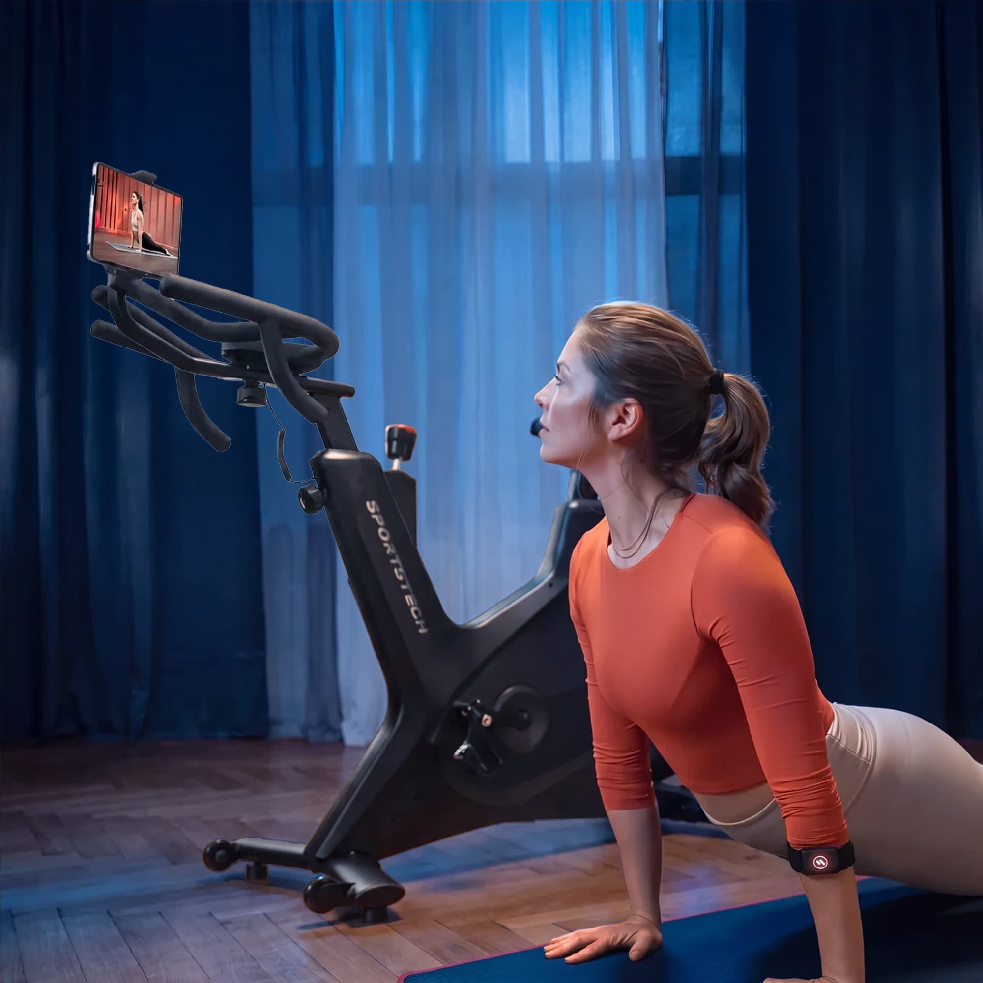 Frau in Plank-Position vor Sportstech Indoor-Bike mit Tablet, sPulse Sensor am Oberschenkel, blaues Ambientelicht
