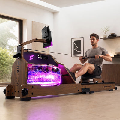 Mann rudert im Wohnzimmer am dunkelbraunen WRX1000, pink leuchtender Wassertank mit WRX1000-Schriftzug