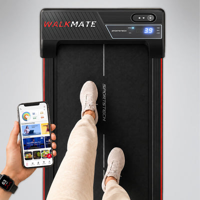 Blick von oben auf Walkmate-Display und Füße, daneben Hand mit App auf dem Smartphone