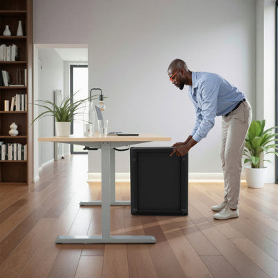 Mann stellt das hochkant zusammengeklappte sWalk Fold Walking Pad neben einen Schreibtisch