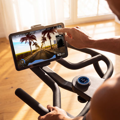 Hand bedient das Tablet am sBike Lite mit Streckenvideo, Drehregler und Lenkergriff im Detail