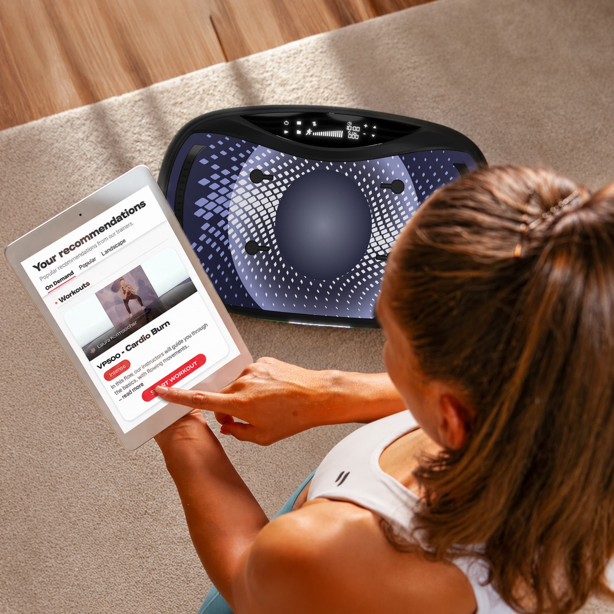 Frau steuert Workout-App auf Tablet neben der VP500 Vibrationsplatte am Boden