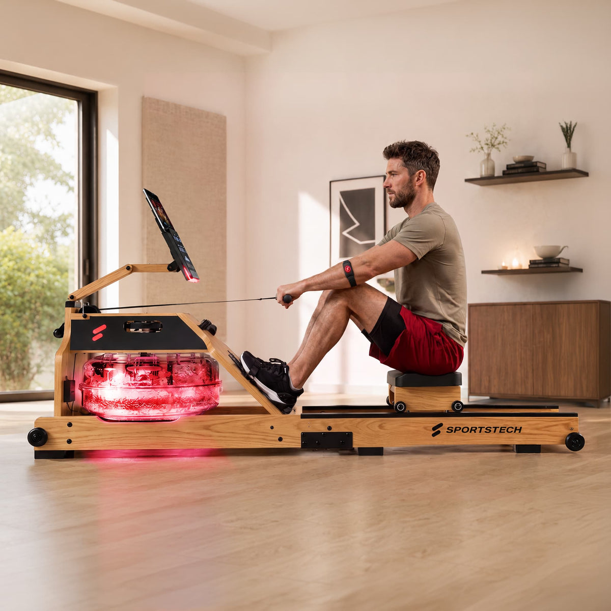 Mann rudert im Wohnzimmer auf dem WRX1000 mit rot beleuchtetem Wassertank und Tablethalterung