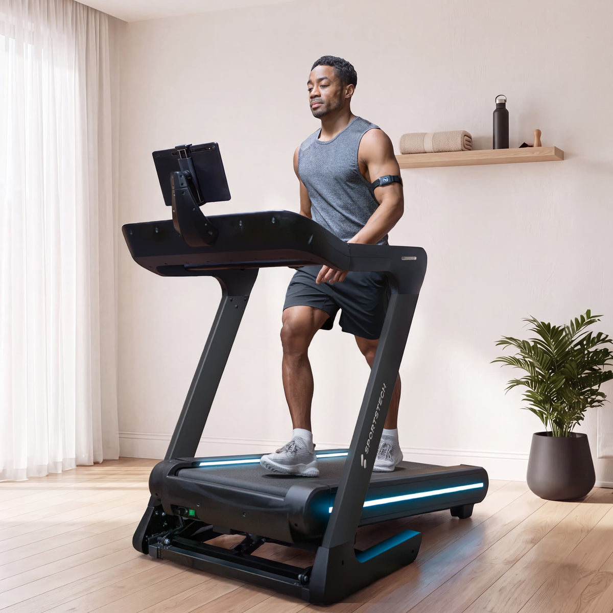 Mann geht auf dem sTread Lite Laufband mit blau beleuchtetem Laufdeck im hellen Wohnzimmer