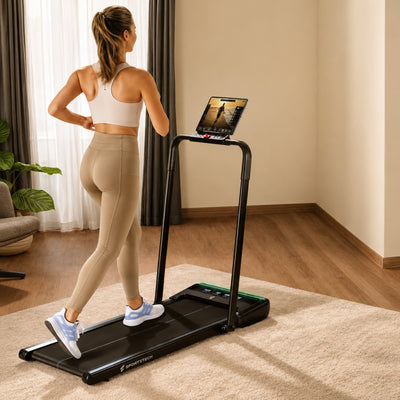 Frau geht im Wohnzimmer auf dem sWalk Lite Plus Laufband mit aufgestelltem Bügel und Tablet in der Halterung
