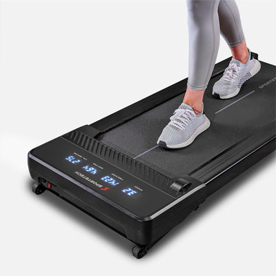 Nahaufnahme des sPad500 Walking Pad mit blau leuchtendem Display und Füßen in Sneakern auf der Lauffläche