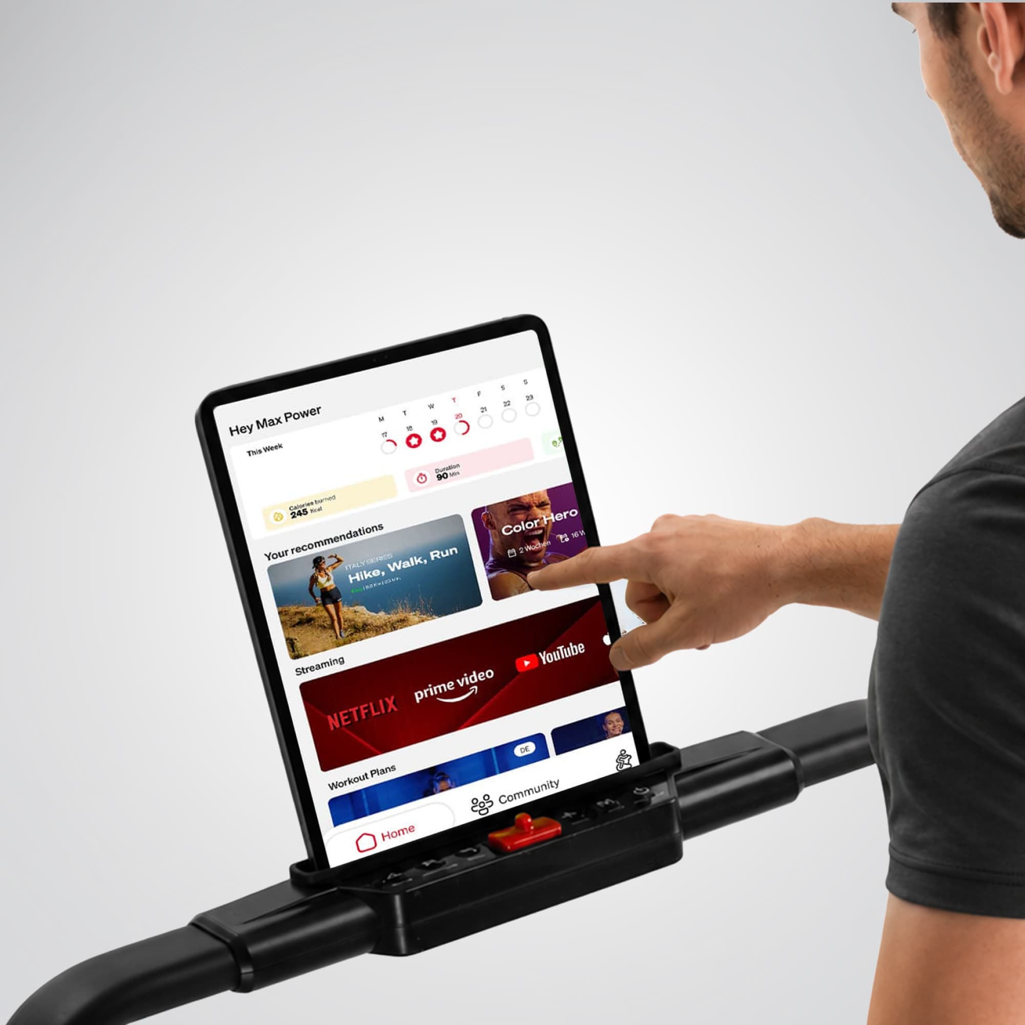 Tablet in der Halterung des sPad1000 zeigt Trainings-App mit Streaming-Diensten, Finger tippt