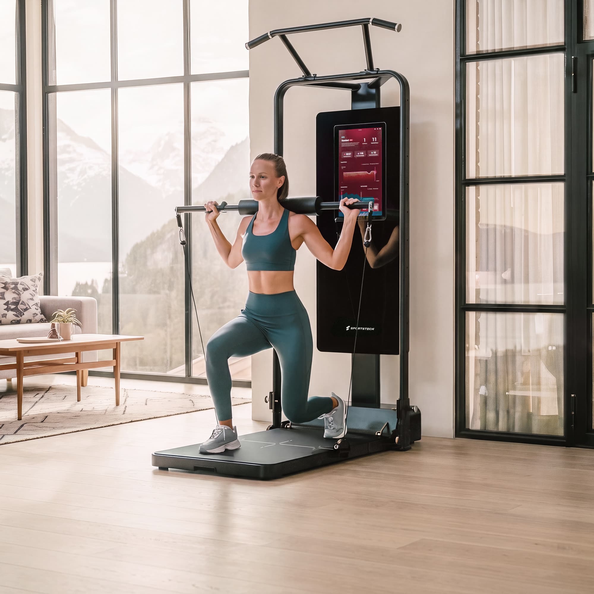 Frau macht Ausfallschritte mit Langhangelstange an der sGym Pro Kraftstation vor Bergpanorama-Fenster