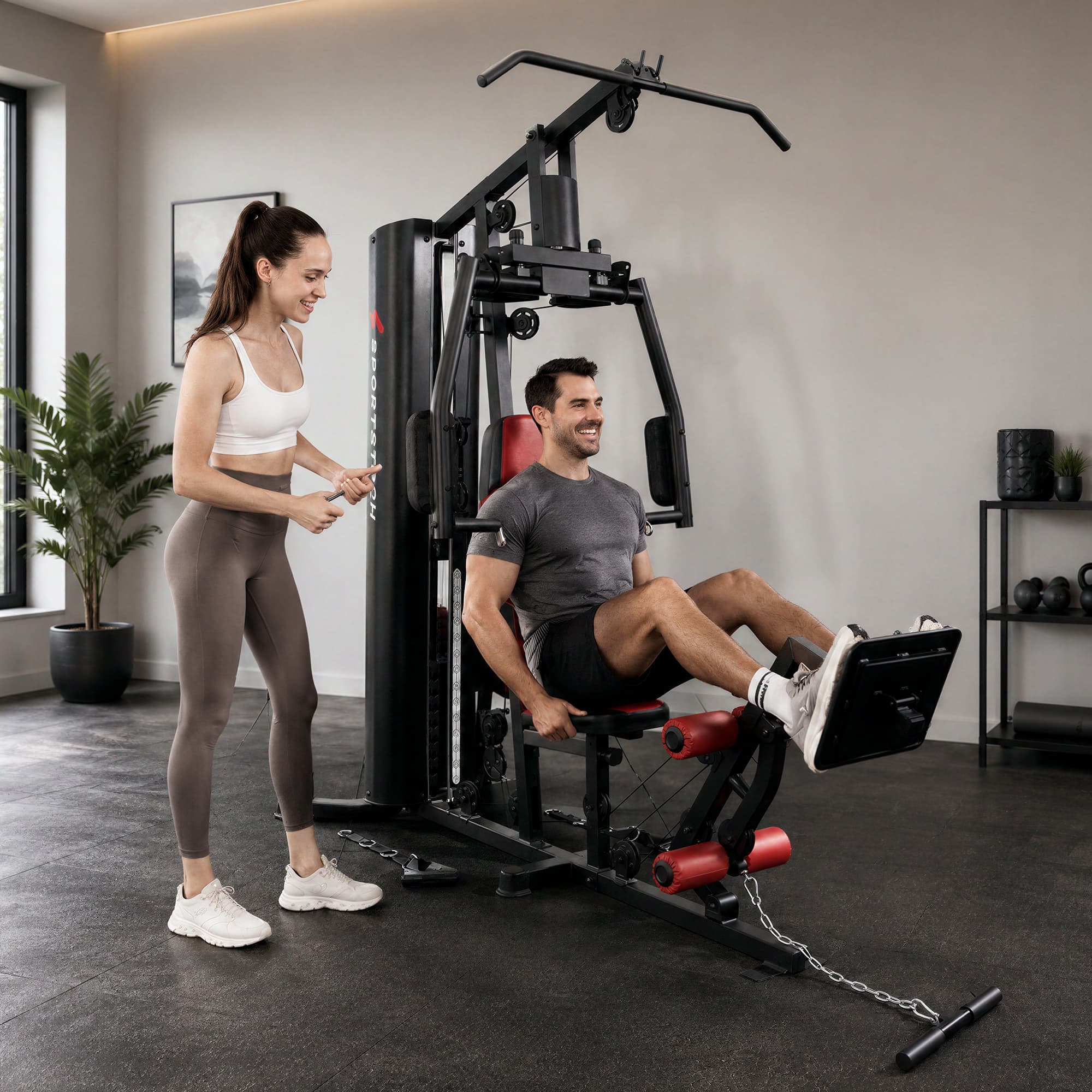 Frau assistiert einem sitzenden Mann bei der Beinstreckung an der HGX150 Kraftstation im Trainingsraum