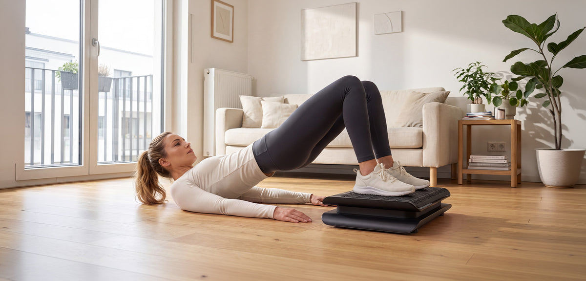 Frau macht eine Glute Bridge mit den Füßen auf der schwarzen sVibe Lite im hellen Wohnzimmer