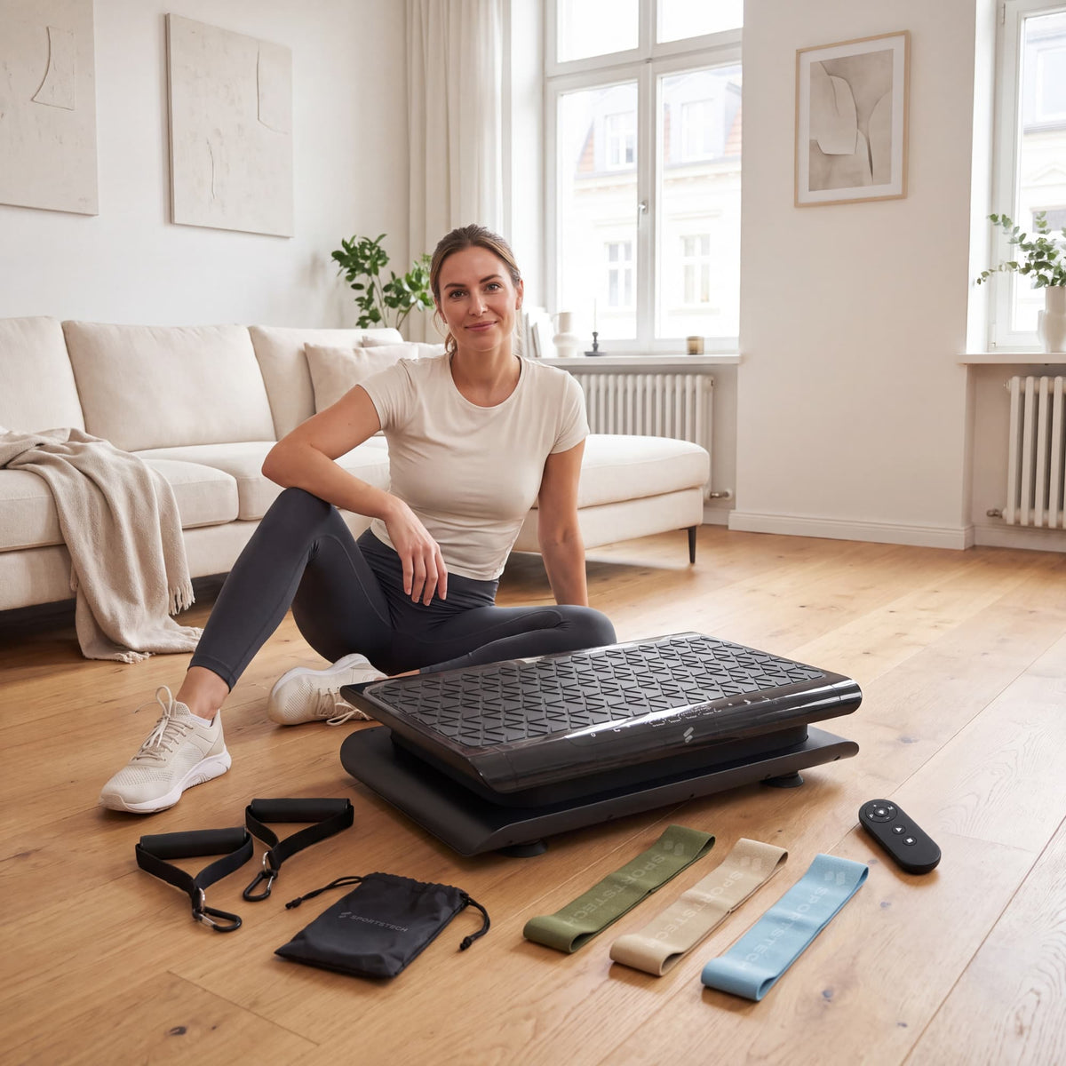 Frau sitzt neben der sVibe Lite mit Zubehör: Expander, drei Loop-Bänder, Beutel und Fernbedienung