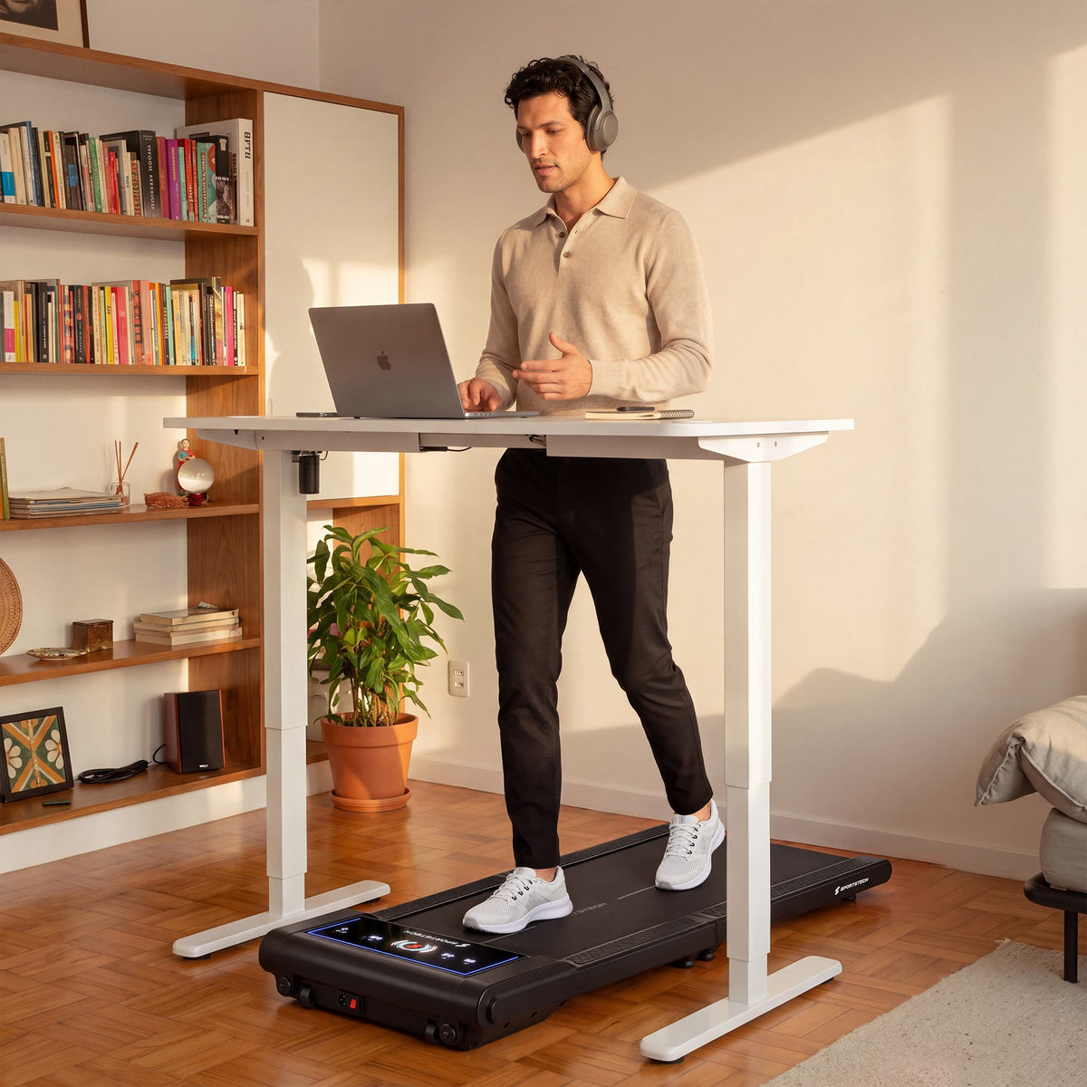 Mann mit Kopfhörern geht am Laptop unter einem Stehschreibtisch auf dem sWalk Fold