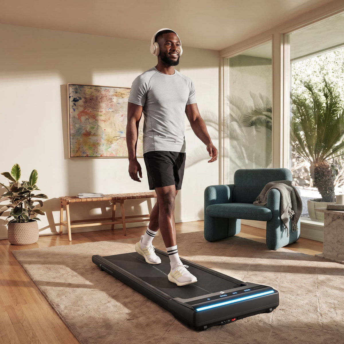 Mann mit Kopfhörern geht im hellen Wohnzimmer auf dem sWalk Lite Walking Pad