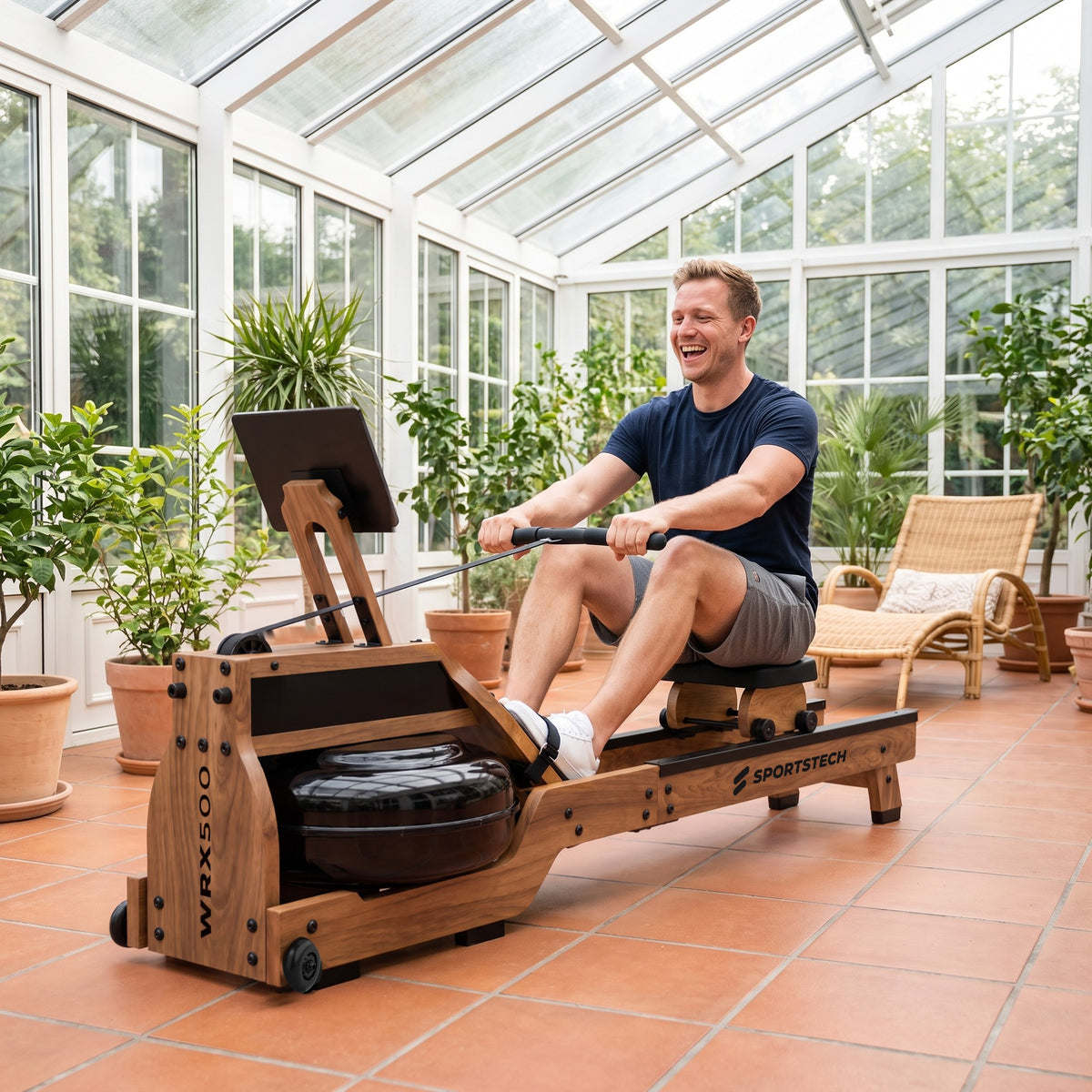 WRX500 Rudergerät aus Holz: Mann rudert im Wintergarten mit Pflanzen