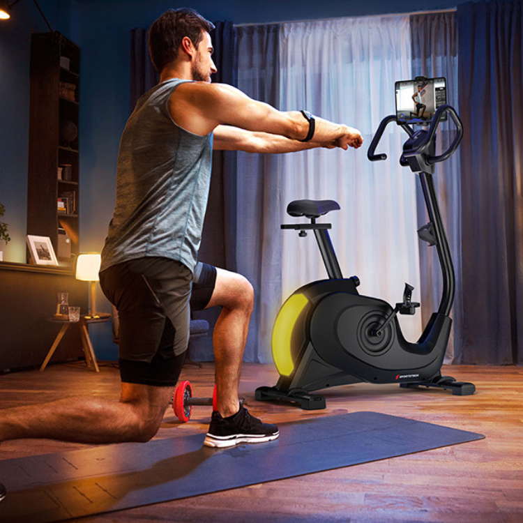 Mann beim Functional-Workout vor einem Ergometer im Wohnzimmer