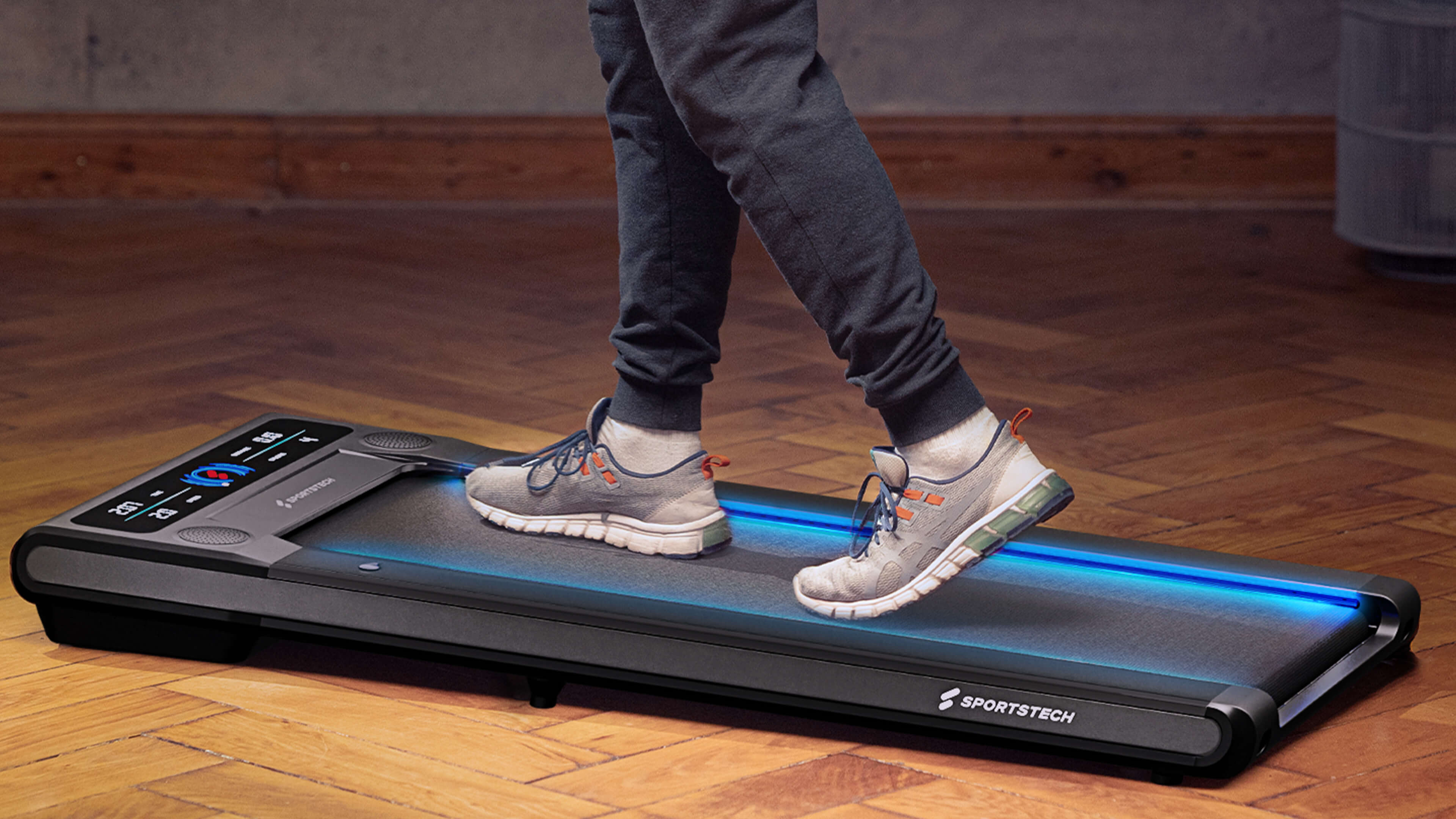 Schwarzes Laufband F10 Sportstech Anwendungen Frau in Sportkleidung klappt schwarzes Laufband F10 zusammen, Mann im Hemd telefoniert auf Laufband, Frau und Mann in Sportkleidung laufen auf Laufband